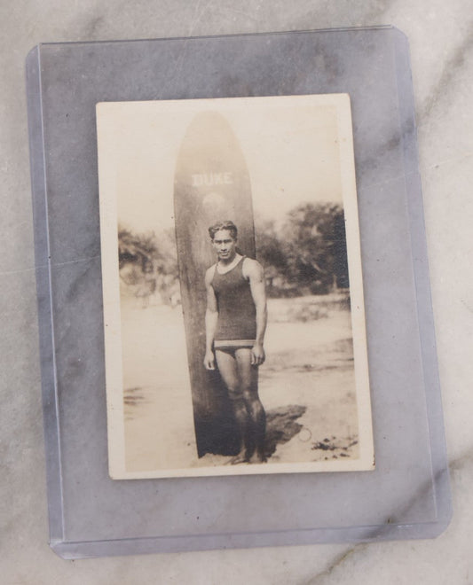 Lot 094 - Single Antique Snapshot Photograph Of An Early 20th Century Surfer Posing With Surfboard, Board Marked "Duke"