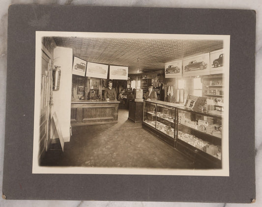 Lot 157 - Vintage Boarded Photograph Of An Early Ford Automobile Car Dealership, With Advertisement For Ford V8 Engine, Select Vehicles, Many Products For Sale, Circa 1930s