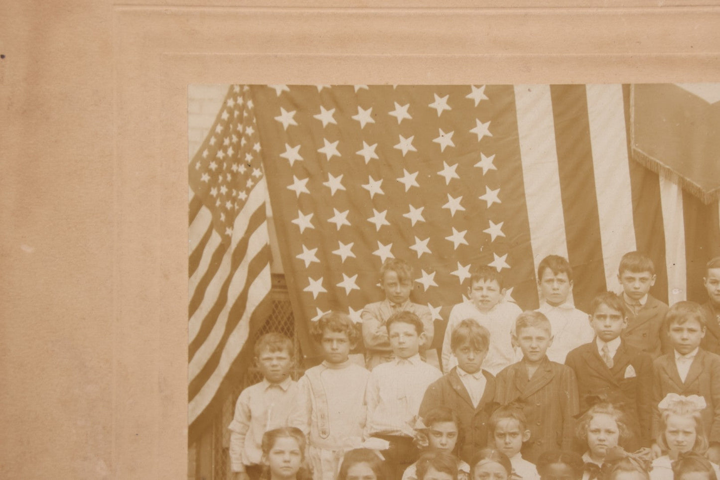 Lot 069 - Antique Boarded Photograph Of An Integrated Elementary School Class, Posing With Large 48 Star American Flag Bunting And Patriotic Decor, Pennants From P.S. 73, Teacher In Photo, Circa 1895