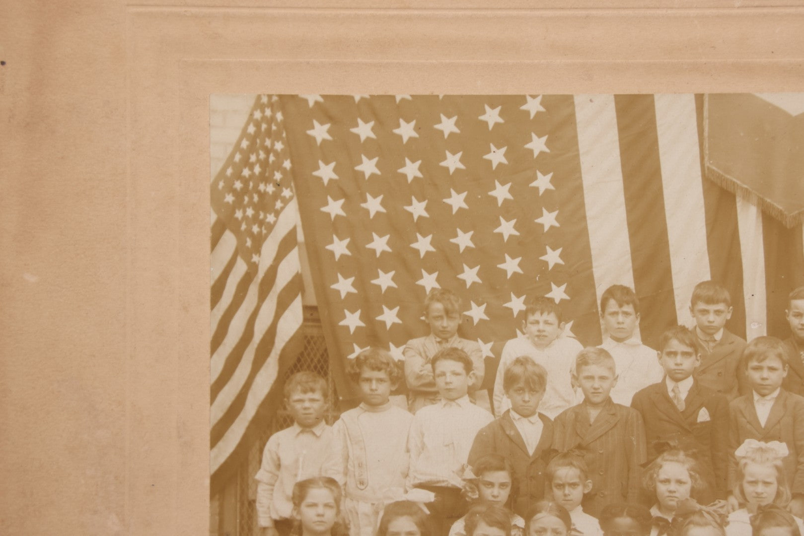 Lot 069 - Antique Boarded Photograph Of An Integrated Elementary School Class, Posing With Large 48 Star American Flag Bunting And Patriotic Decor, Pennants From P.S. 73, Teacher In Photo, Circa 1895