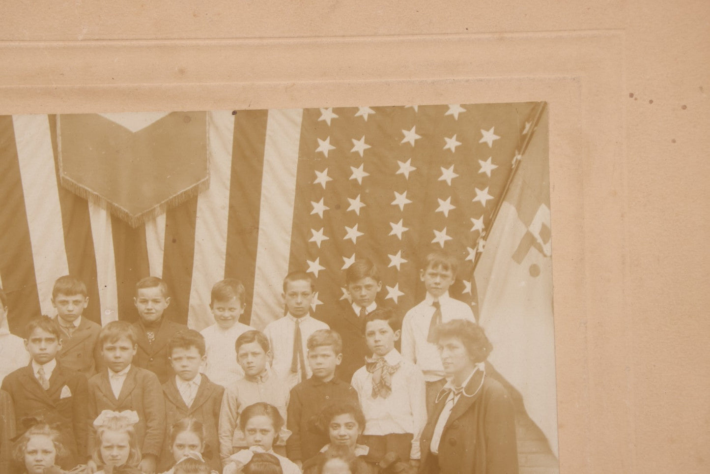 Lot 069 - Antique Boarded Photograph Of An Integrated Elementary School Class, Posing With Large 48 Star American Flag Bunting And Patriotic Decor, Pennants From P.S. 73, Teacher In Photo, Circa 1895