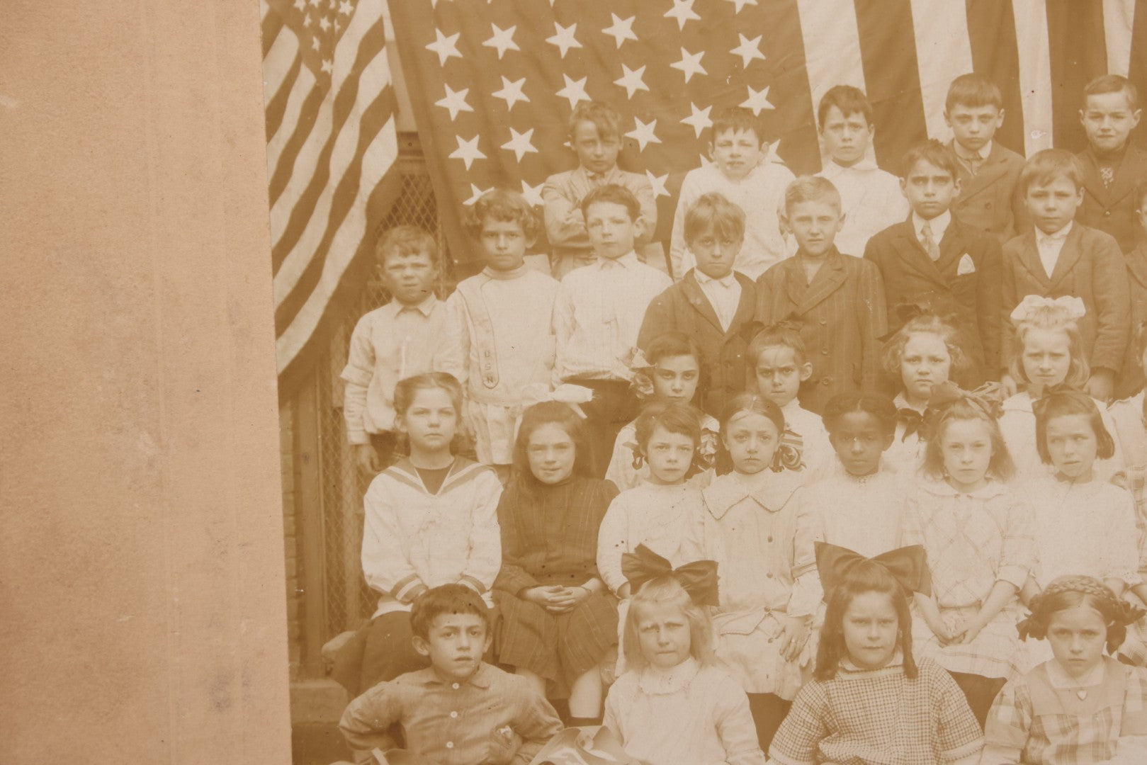 Lot 069 - Antique Boarded Photograph Of An Integrated Elementary School Class, Posing With Large 48 Star American Flag Bunting And Patriotic Decor, Pennants From P.S. 73, Teacher In Photo, Circa 1895