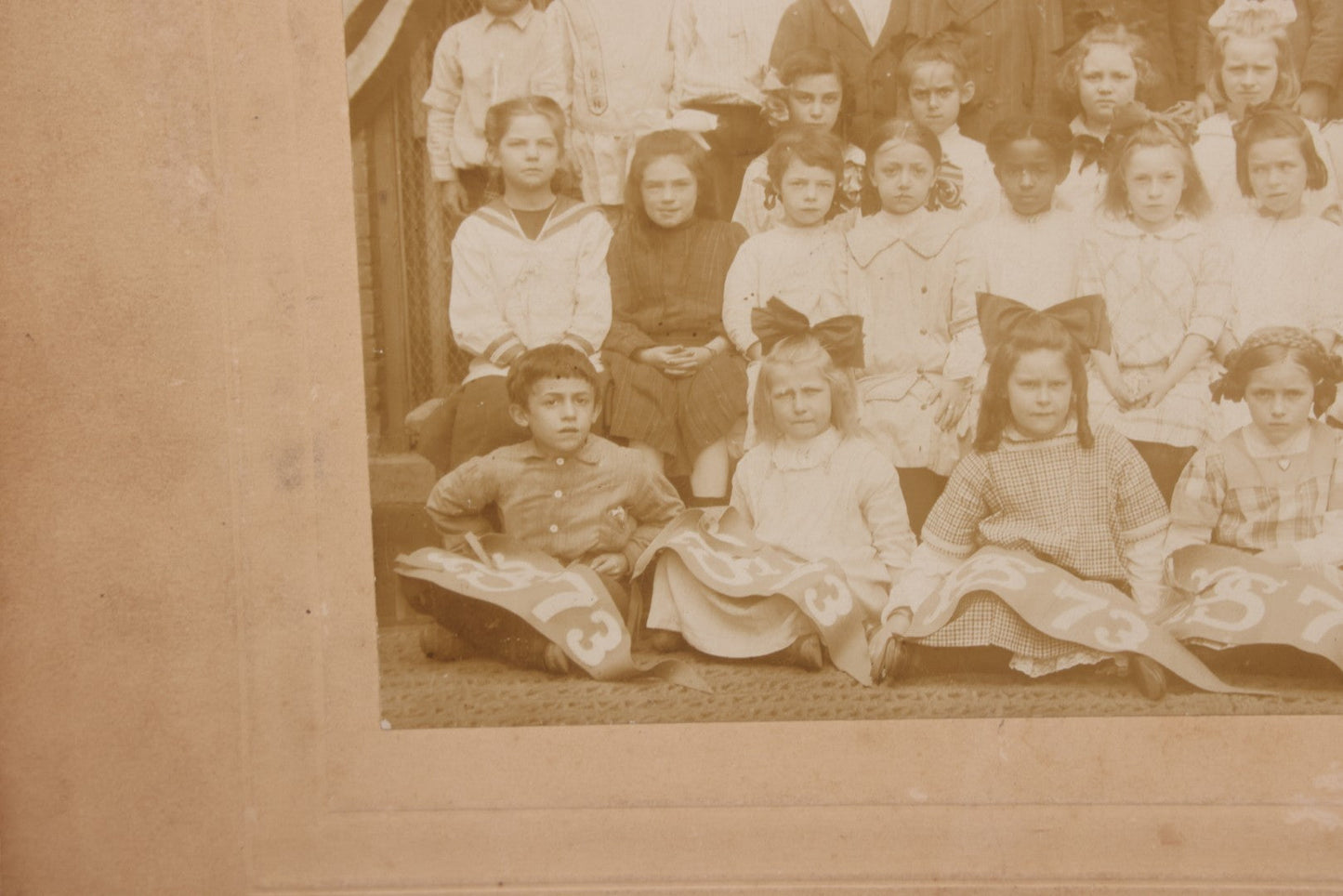 Lot 069 - Antique Boarded Photograph Of An Integrated Elementary School Class, Posing With Large 48 Star American Flag Bunting And Patriotic Decor, Pennants From P.S. 73, Teacher In Photo, Circa 1895
