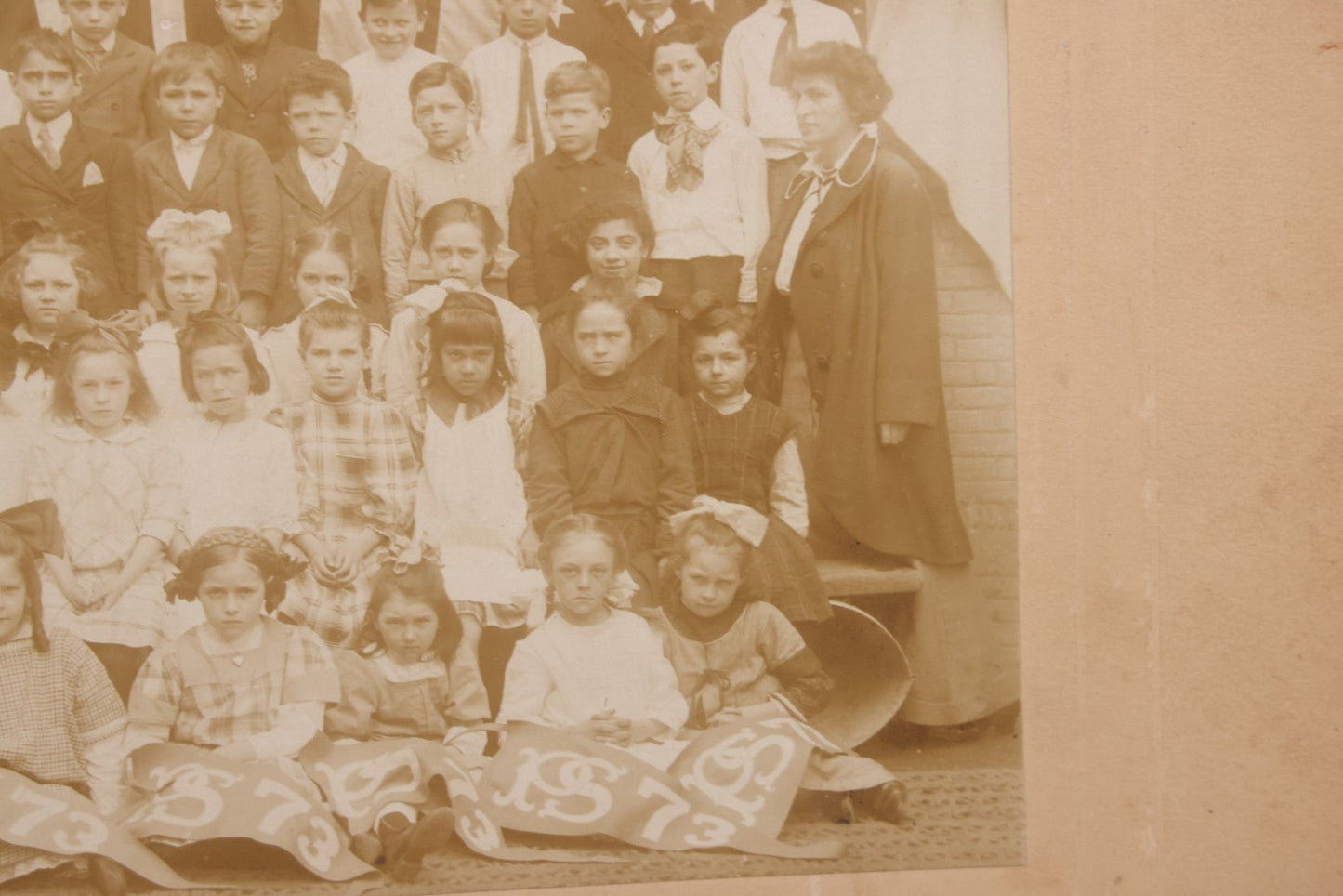 Lot 069 - Antique Boarded Photograph Of An Integrated Elementary School Class, Posing With Large 48 Star American Flag Bunting And Patriotic Decor, Pennants From P.S. 73, Teacher In Photo, Circa 1895