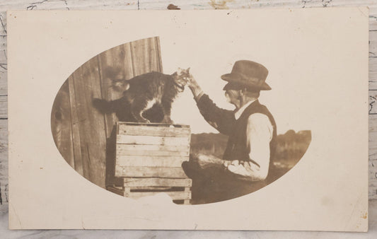 Lot 070 - Antique Unmounted Paper Photograph Of Old Man Petting Cat Standing On Crates, Postcard Style Paper