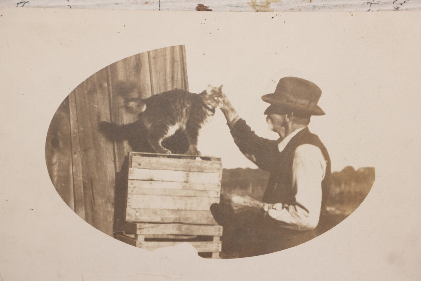 Lot 070 - Antique Unmounted Paper Photograph Of Old Man Petting Cat Standing On Crates, Postcard Style Paper