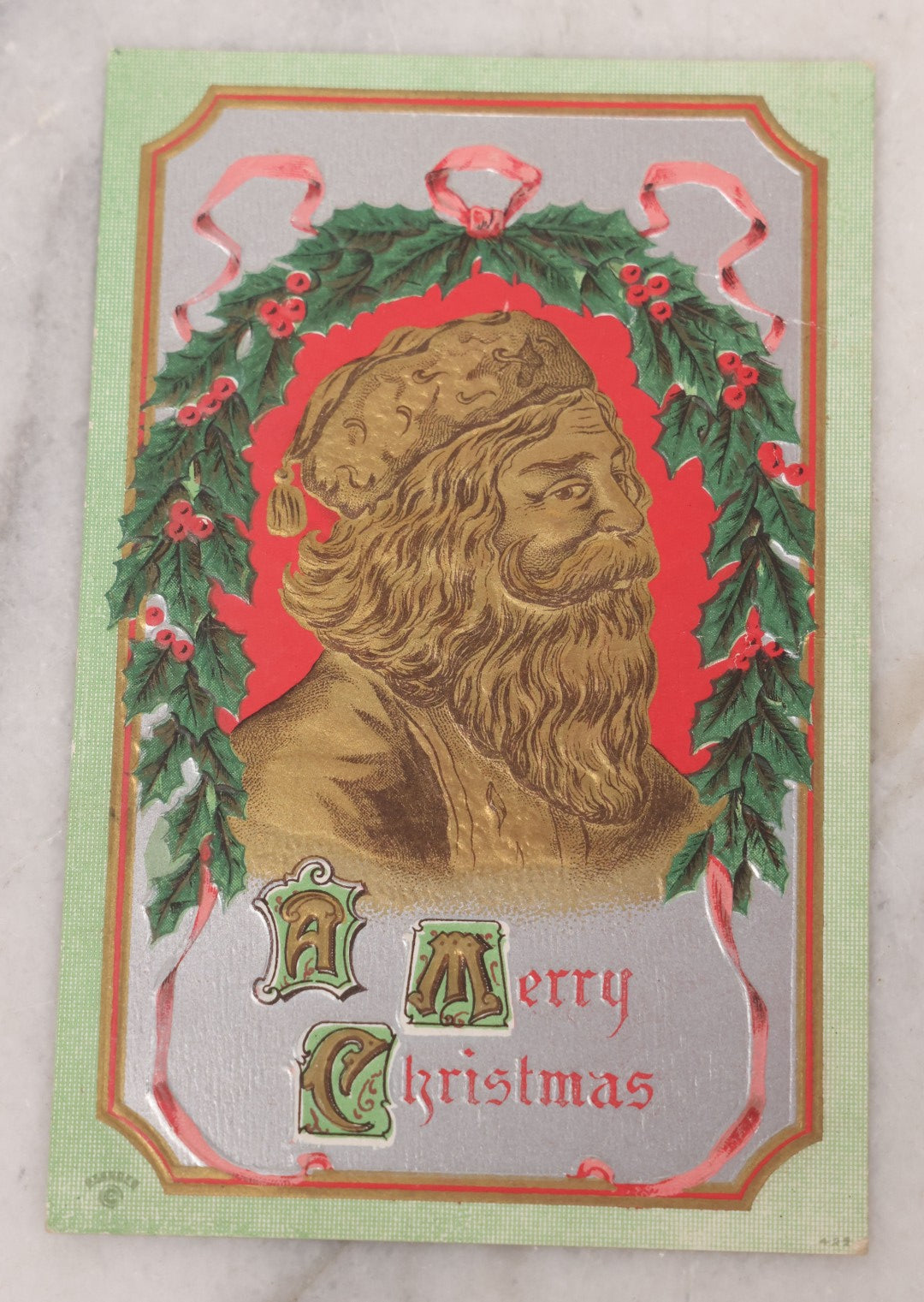 Lot 097 - Antique Embossed Christmas Postcard, "A Merry Christmas" Featuring Gold Saint Nick Santa With Mistletoe And Ribbon Border, Circa 1910