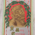 Lot 097 - Antique Embossed Christmas Postcard, "A Merry Christmas" Featuring Gold Saint Nick Santa With Mistletoe And Ribbon Border, Circa 1910