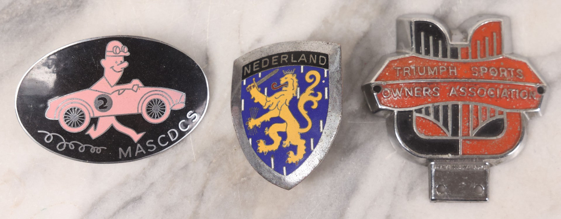 Lot 034 - Grouping Of Three Vintage Automobile Badges Including Nederland Lion Crest, Triumph Sports Owners Association, And M.A.S.C.D.C.S. Car Club