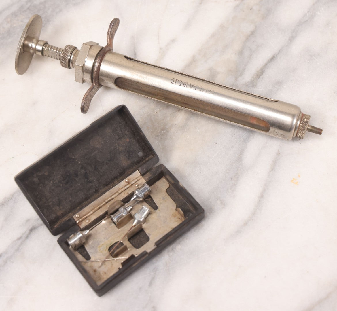 Lot 045 - Antique “Reliable” Brand Syringe No. 3 With Metal Body And Glass Center Tube, With Box Of Vintage B.D. Needles