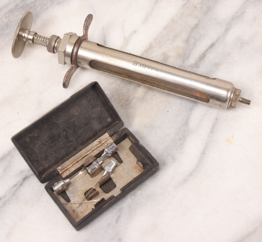 Lot 045 - Antique “Reliable” Brand Syringe No. 3 With Metal Body And Glass Center Tube, With Box Of Vintage B.D. Needles