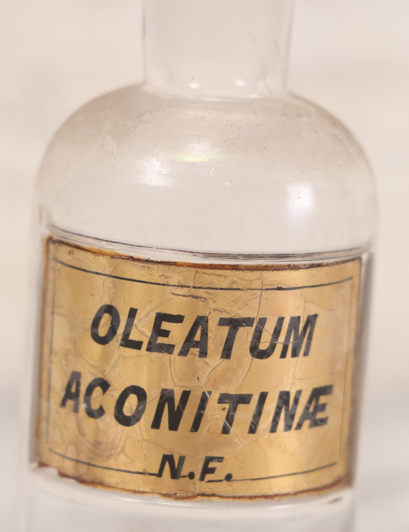 Lot 057 - Antique Whitall Tatum Co. Clear Glass Apothecary Bottle With Stopper And Reverse Painted Label “Oleatum Aconitinae N.F.” Small Size, 5-1/2" H