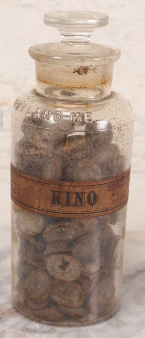 Lot 058 - Antique Apothecary Bottle With Original Paper Label “Kino, London Hospital Throat Lozenges” With Contents, Clear Glass Bottle With Stopper Manufactured By George C. Frye, Portland, Maine, 8" H