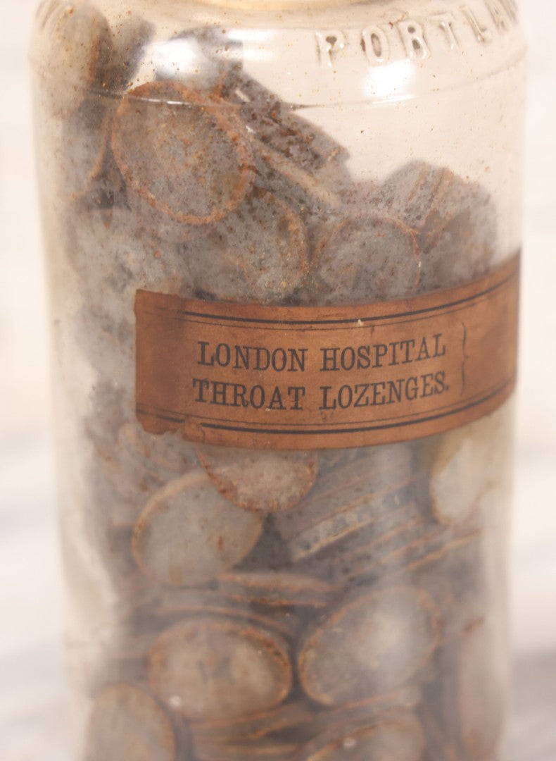Lot 058 - Antique Apothecary Bottle With Original Paper Label “Kino, London Hospital Throat Lozenges” With Contents, Clear Glass Bottle With Stopper Manufactured By George C. Frye, Portland, Maine, 8" H