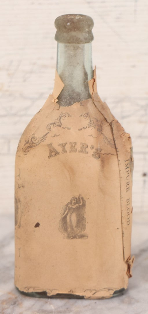 Lot 059 - Antique Ayer's Clear Glass Bottle With Partial Paper Label Wrapper And Embossed Base, 7-1/2" H