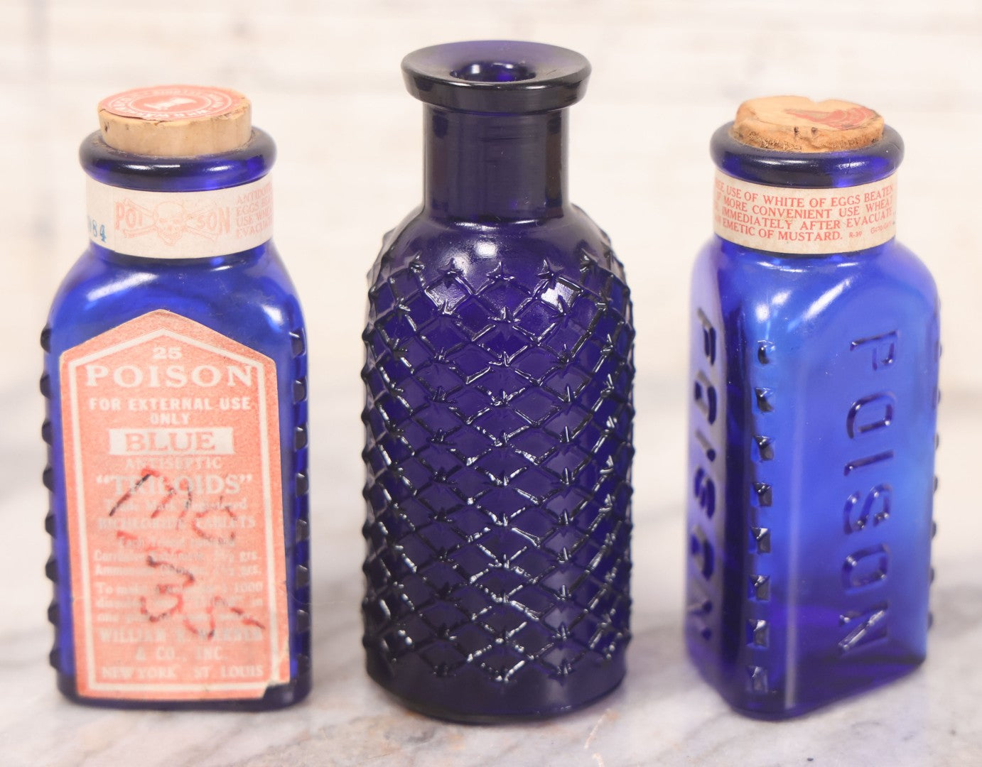 Lot 067 - Grouping Of Three Antique Small Cobalt Blue Glass Poison Bottles, Including Crosshatch Poison Ribbed And Two Triangular “Antiseptic Triloids” Bottles By William R. Warner & Co. Inc., New York & St. Louis, With Paper Labels