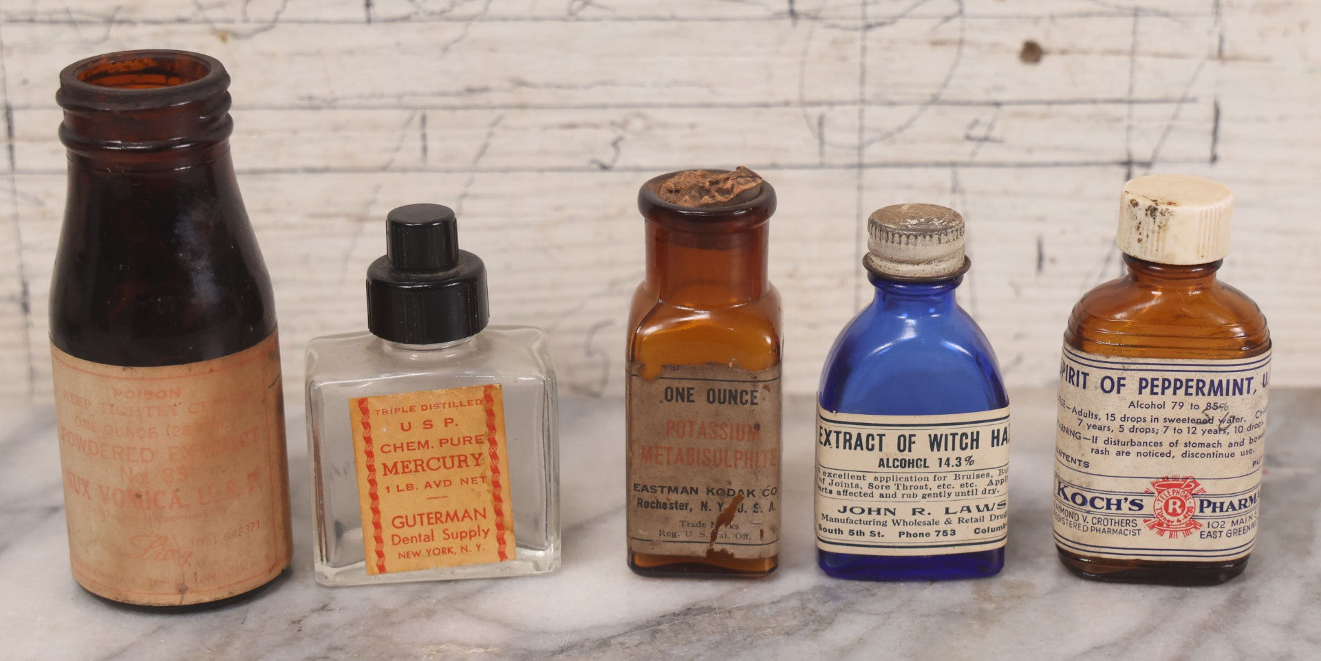Lot 073 - Grouping Of Five Antique Bottles With Paper Labels Including Witch Hazel, John Laws, Columbus M.S., Spirit Of Peppermint, Koch's Pharm., Greenwich, R.I., Potassium Metabisulphate, Kodak, Mercury, Guterman Dental, N.Y., & Nux Vomica