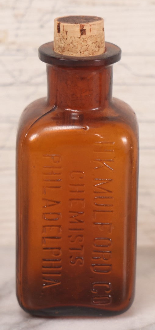 Lot 075 - Grouping Of Four Antique Amber Glass Bottles Including Cramp Bark From Sharp & Dohme, Baltimore, Sanguinaria From John Wyeth & Brother, Philadelphia, H.K. Mulford Co., Philadelphia, And One Unmarked With Stopper