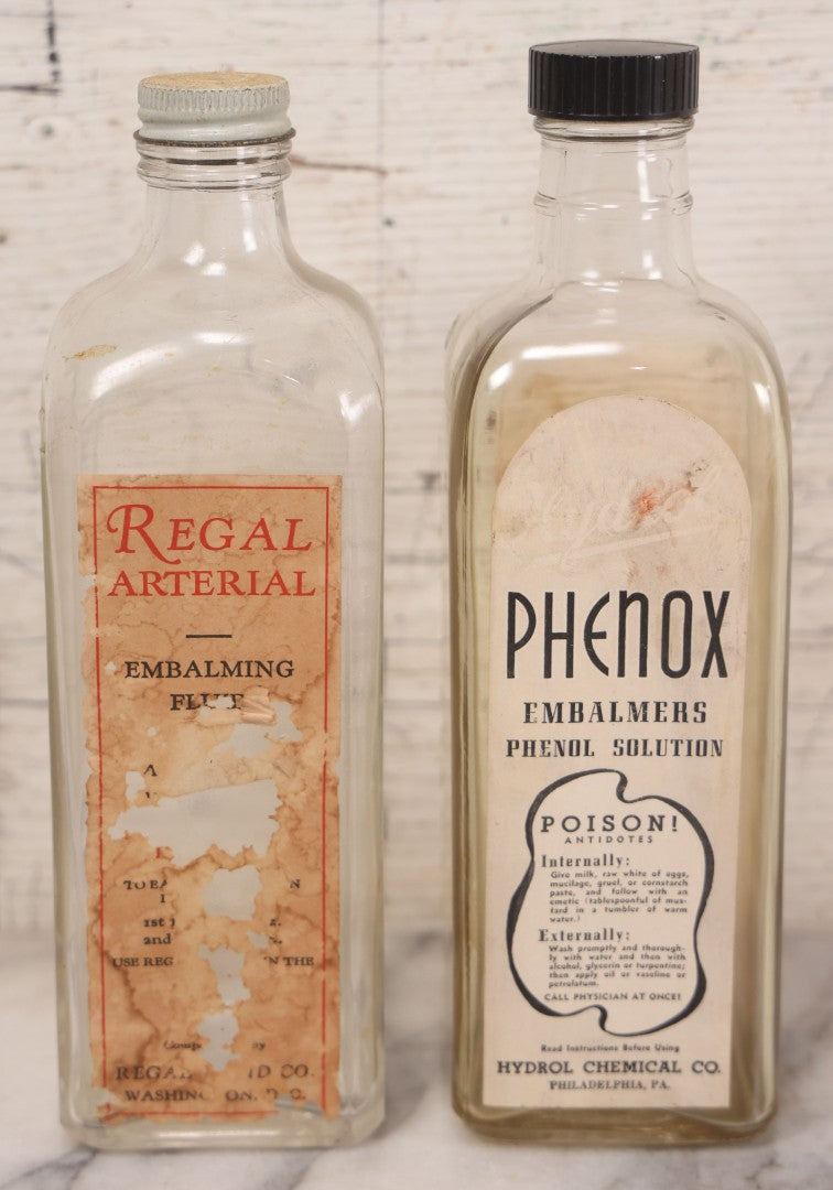Lot 077 - Pair Of Vintage Clear Glass Embalming Fluid Bottles With Paper Labels And Caps Including Regal Arterial From Regal Fluid Co., Washington, D.C., And Hydrol Phenox From Hydrol Chemical Co., Philadelphia