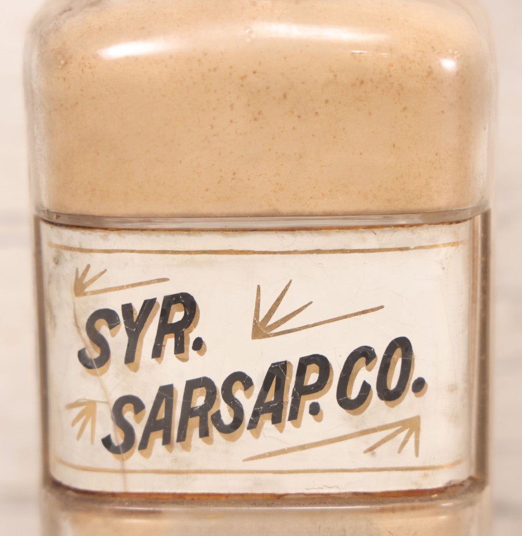 Lot 080 - Grouping Of Three Antique Whitall Tatum Co. Clear Glass Apothecary Bottles With Stoppers And Partial Reverse Painted Labels Including Syr. Sarsap. Co., Saponis, And Tragacanth