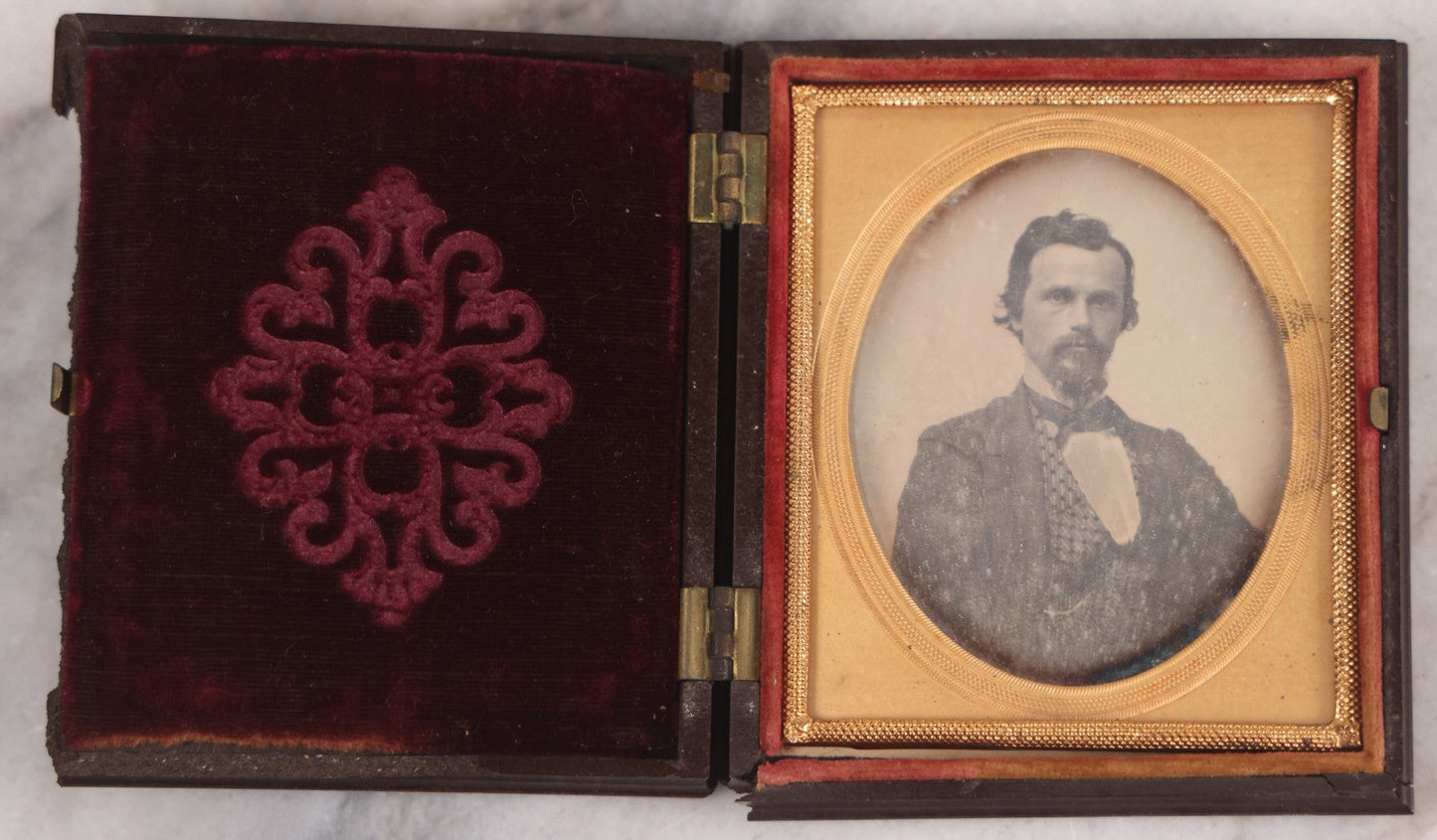 Lot 094 - Antique 1/6th Plate Daguerreotype Photograph Of Man In Full Thermoplastic Case With Abstract Floral Design, Brass Mat, Dark Red Cushion, Heavily Speckled Surface Of Photograph, Note Damage To Case