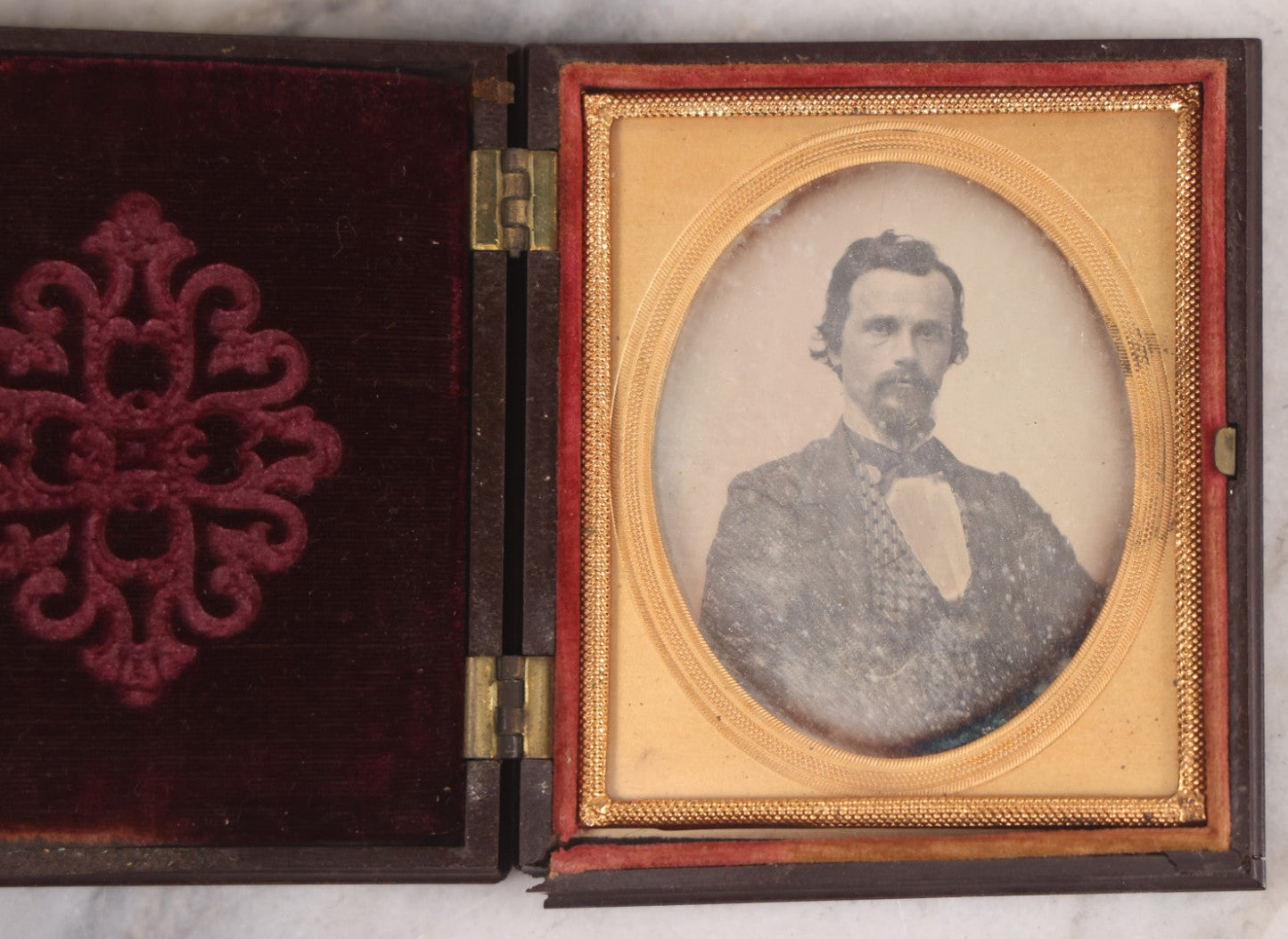 Lot 094 - Antique 1/6th Plate Daguerreotype Photograph Of Man In Full Thermoplastic Case With Abstract Floral Design, Brass Mat, Dark Red Cushion, Heavily Speckled Surface Of Photograph, Note Damage To Case