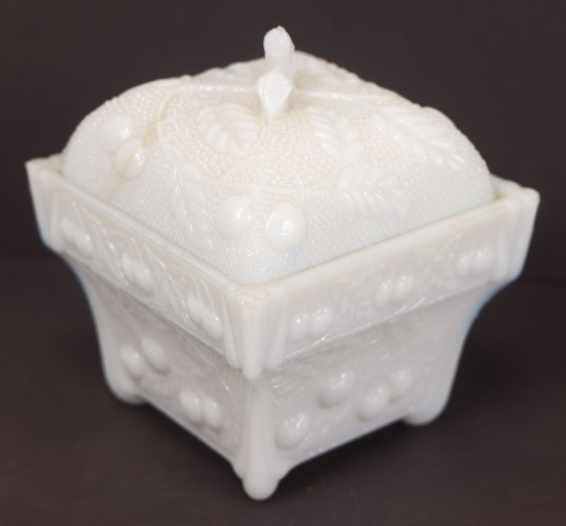 Lot 135 - Antique Milk Glass Covered Dish With Embossed Fruit And Leaf Design On Four Feet, Note Chipped Corner
