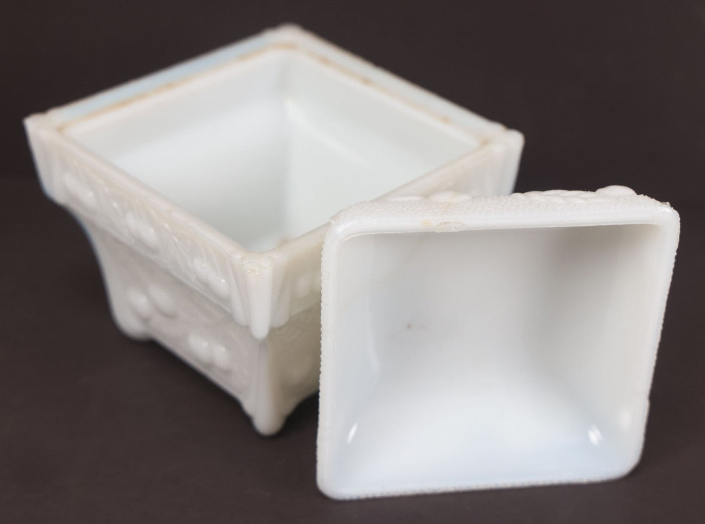 Lot 135 - Antique Milk Glass Covered Dish With Embossed Fruit And Leaf Design On Four Feet, Note Chipped Corner