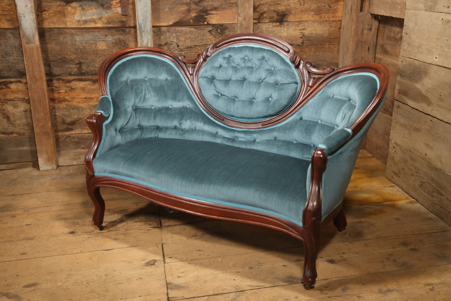 Antique Victorian Carved Walnut Settee With Tufted Blue Upholstery And Casters
