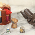 Lot 107 - Antique And Vintage Sewing Lot Including Marbled Plastic Thread Holder With Pin Cushion, Metal Mushroom Thread Holder, Two Thimbles, And Cast Iron Table Clamp Thread Holder By Herter's, Waseca Minn., No. 29