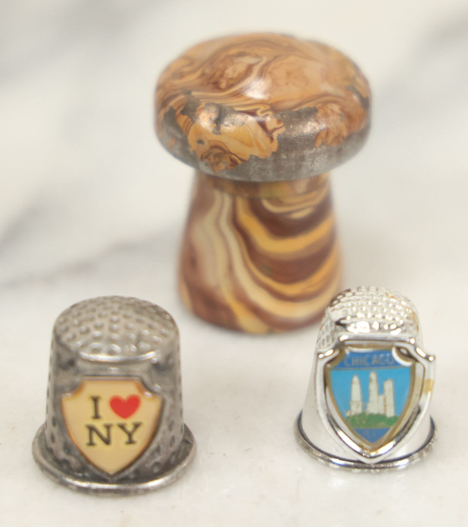 Lot 107 - Antique And Vintage Sewing Lot Including Marbled Plastic Thread Holder With Pin Cushion, Metal Mushroom Thread Holder, Two Thimbles, And Cast Iron Table Clamp Thread Holder By Herter's, Waseca Minn., No. 29