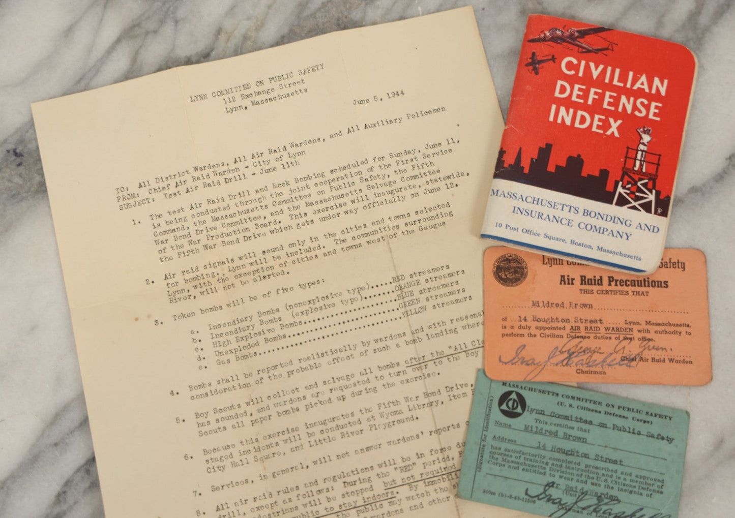 Lot 193 - Grouping Of Four Vintage World War II Civil Defense Ephemera Items, Including Air Raid Drill Letter (June 5, 1944), Civilian Defense Index Booklet, Lynn Air Raid Precautions Warden Card, And Identification Card For Mildred Brown
