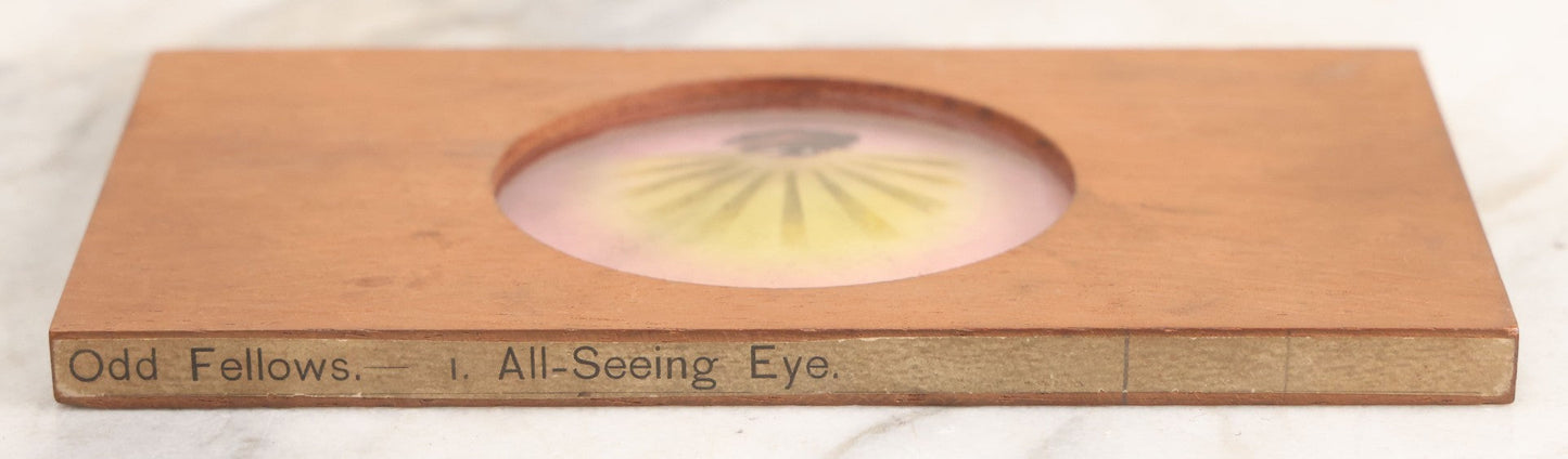 Lot 017 - Antique Hand Colored Odd Fellows I.O.O.F. Magic Lantern Glass Slide With Wood Holder, No. 1 All-Seeing Eye, Manufactured By The Henderson-Ames Co., Kalamazoo, Michigan