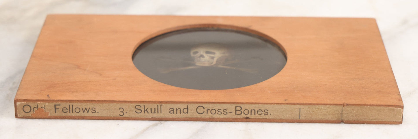 Lot 019 - Antique Hand Colored Odd Fellows I.O.O.F. Magic Lantern Glass Slide With Wood Holder, No. 3 Skull And Cross-Bones, Manufactured By The Henderson-Ames Co., Kalamazoo, Michigan
