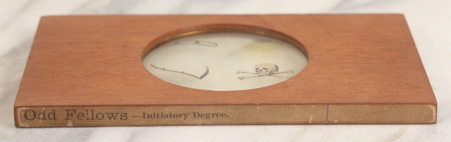 Lot 033 - Antique Hand Colored Odd Fellows I.O.O.F. Magic Lantern Glass Slide With Wood Holder, Initiatory Degree, Depicting The Three Links, Scythe, Skull And Cross-Bones, And All-Seeing Eye, Manufactured By The Henderson-Ames Co., Kalamazoo, Michigan