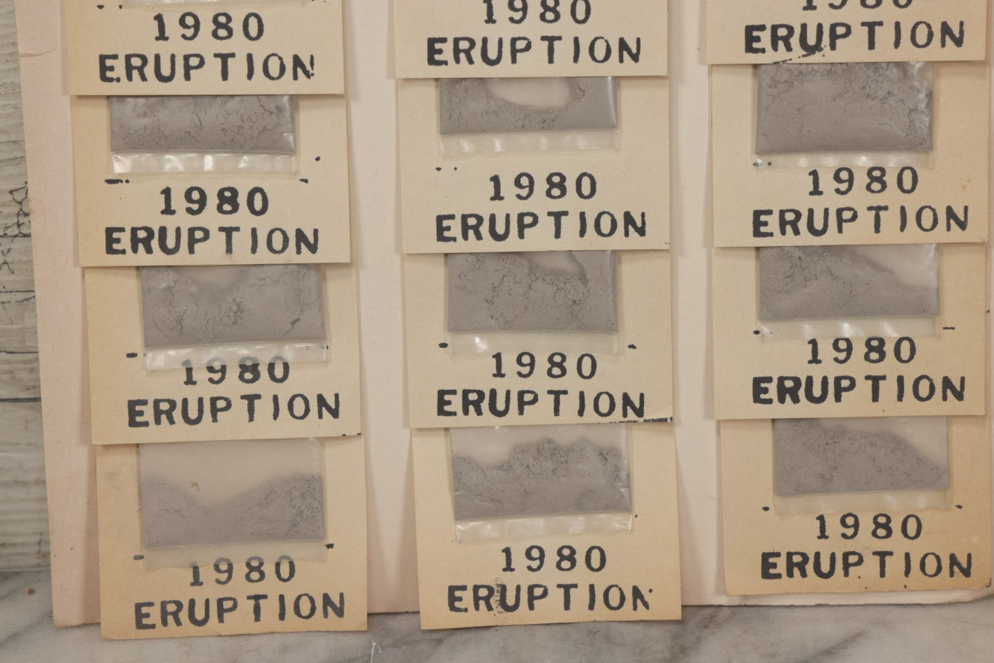 Lot 034 - Vintage Souvenir Display Board Of “Mt. St. Helens Volcanic Ash, 1980 Eruption,” With 13 Remaining Samples