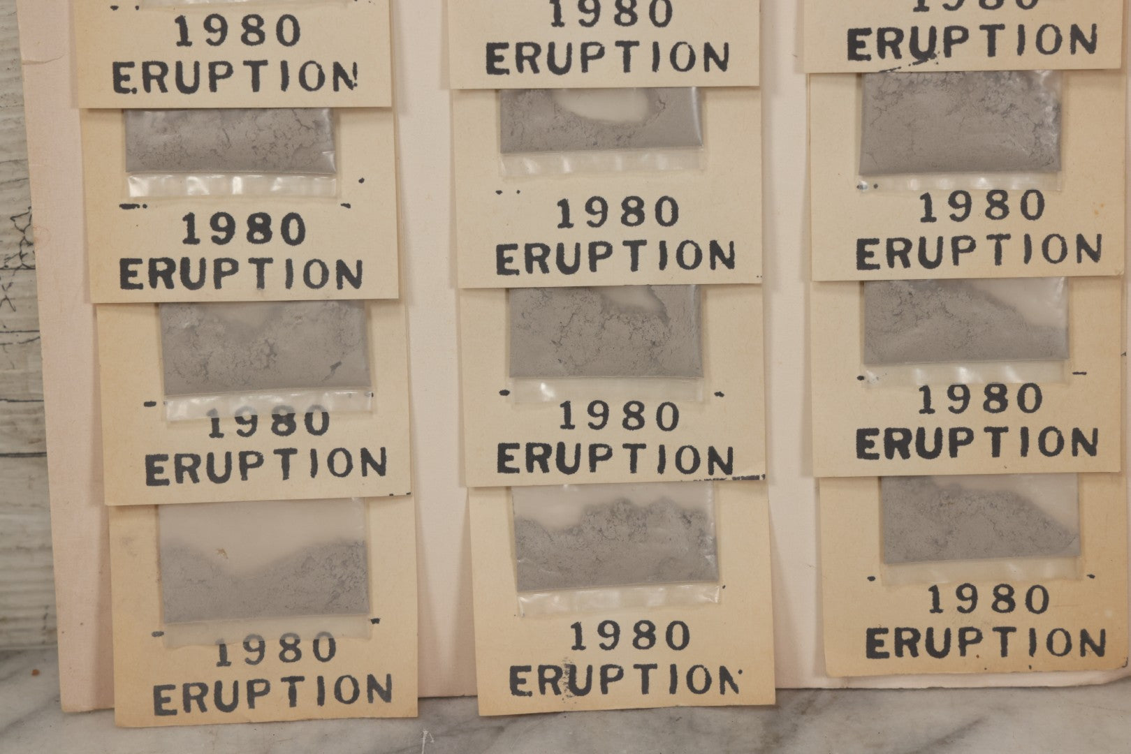 Lot 034 - Vintage Souvenir Display Board Of “Mt. St. Helens Volcanic Ash, 1980 Eruption,” With 13 Remaining Samples