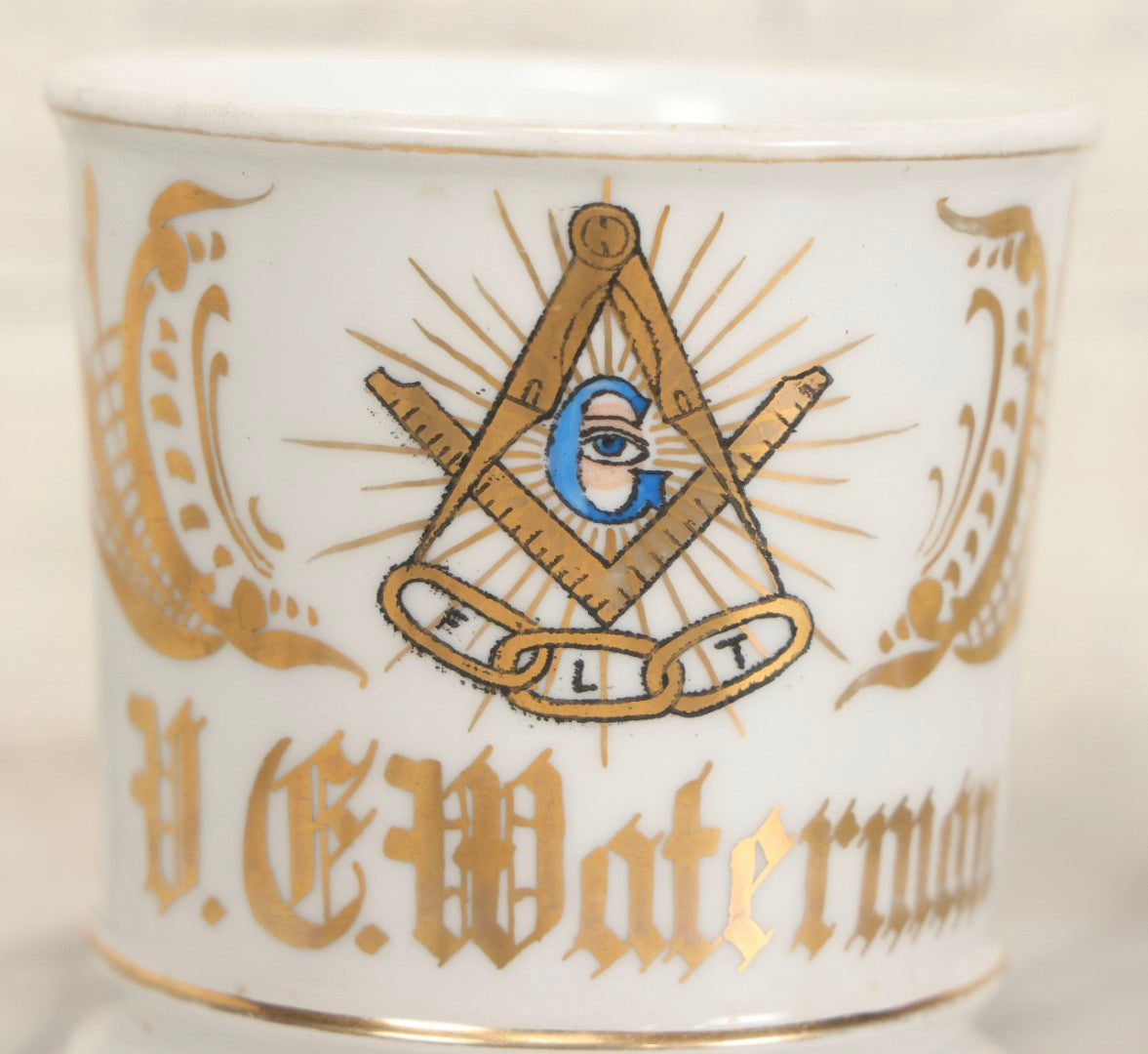 Lot 047 - Antique Hand-Decorated Porcelain Mug With Masonic Compass And Square, All-Seeing Eye, And Odd Fellows Three-Link F.L.T. Emblems, Belonging To V.E. Waterman, With Gold Painted Accents, T&V Limoges, France, 3-5/8" H
