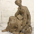 Lot 057 - Antique Cast Spelter Metal Clock Topper Statue With Bronze Wash Depicting Goddess-Like Woman Beside Gear, Anvil, And Blacksmith's Hammer, 8-1/2" H