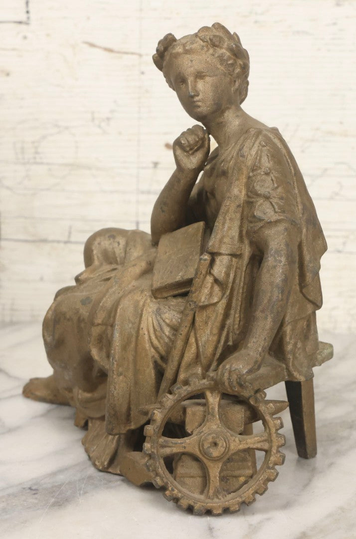 Lot 057 - Antique Cast Spelter Metal Clock Topper Statue With Bronze Wash Depicting Goddess-Like Woman Beside Gear, Anvil, And Blacksmith's Hammer, 8-1/2" H