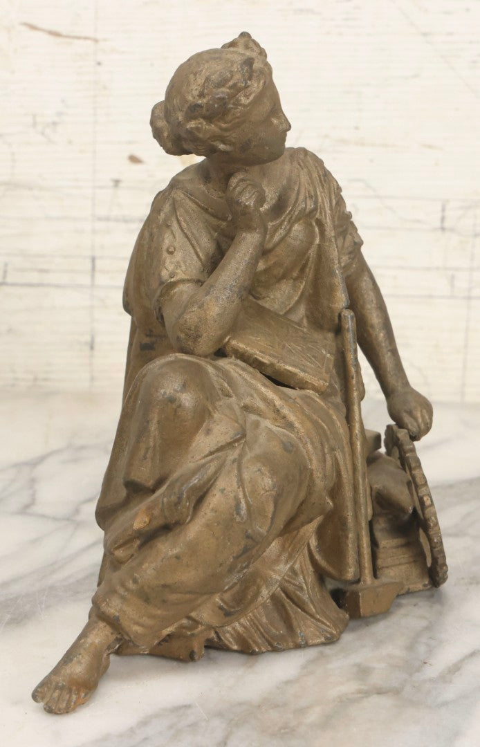 Lot 057 - Antique Cast Spelter Metal Clock Topper Statue With Bronze Wash Depicting Goddess-Like Woman Beside Gear, Anvil, And Blacksmith's Hammer, 8-1/2" H