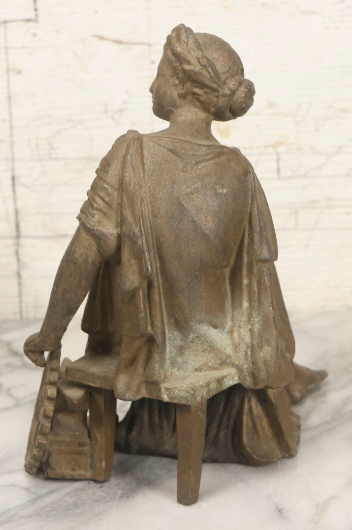 Lot 057 - Antique Cast Spelter Metal Clock Topper Statue With Bronze Wash Depicting Goddess-Like Woman Beside Gear, Anvil, And Blacksmith's Hammer, 8-1/2" H