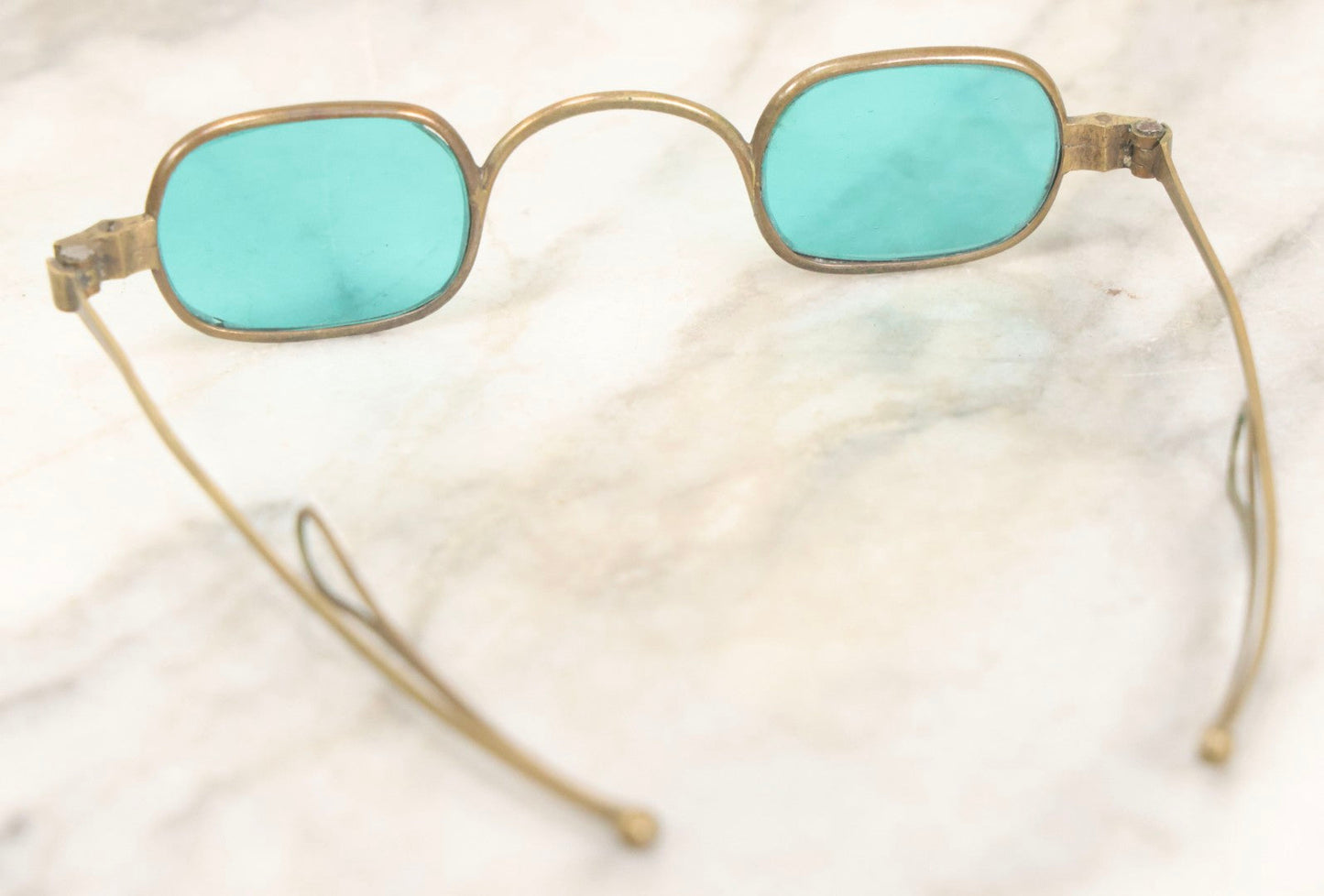 Lot 065 - Antique Brass Frame Eyeglasses With Blue-Green Tinted Lenses And Folding Side Extensions, In Black Lacquered Papier-Mâché Case With Gilt Detailing