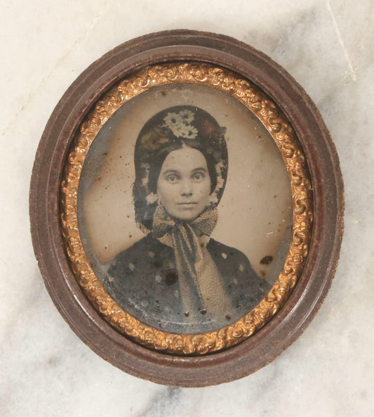 Lot 164 - Antique Oval-Cut Tintype Photograph Of Woman In Bonnet With Flowers And Bow Scarf, In Brown Thermoplastic “Oreo”-Style Case With Brass Preserver, 1-7/8" x 2-1/8"