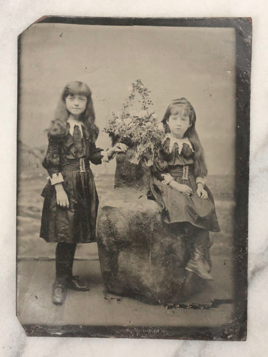 Lot 166 - Antique 1/4 Plate Tintype Photograph Of Two Young Girls In Matching Dresses Posed In Studio Beach Scene With Floral Bouquet And Coastal Background