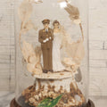 Lot 035 - Vintage Wwii Era Servicemember Wedding Cake Topper In Glass Dome Cloche With Bride, Groom In Military Uniform, Faux White Flowers, And Wood Base, 9-1/2" H
