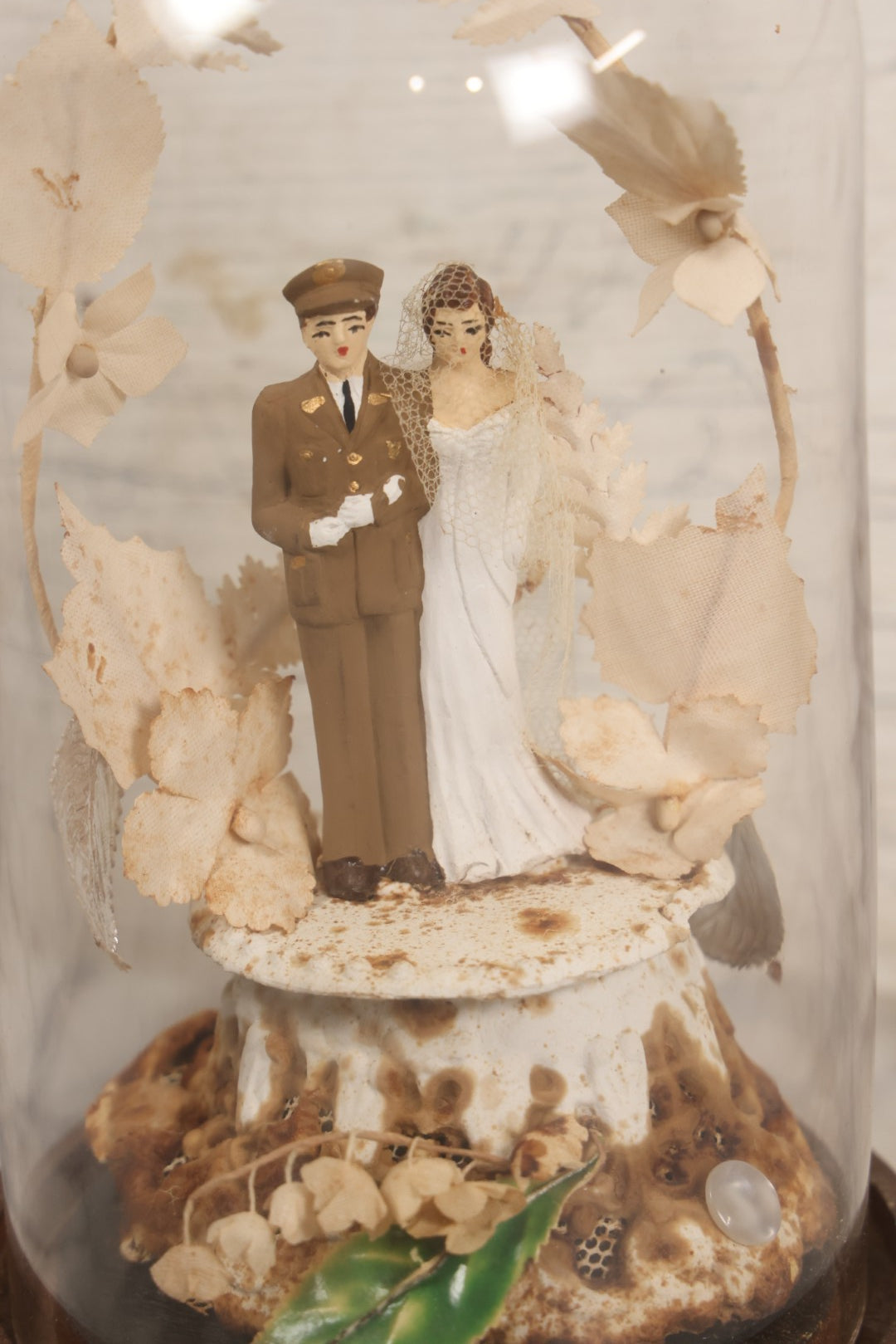 Lot 035 - Vintage Wwii Era Servicemember Wedding Cake Topper In Glass Dome Cloche With Bride, Groom In Military Uniform, Faux White Flowers, And Wood Base, 9-1/2" H