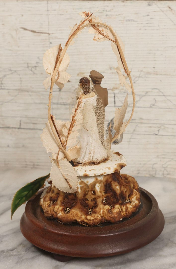 Lot 035 - Vintage Wwii Era Servicemember Wedding Cake Topper In Glass Dome Cloche With Bride, Groom In Military Uniform, Faux White Flowers, And Wood Base, 9-1/2" H