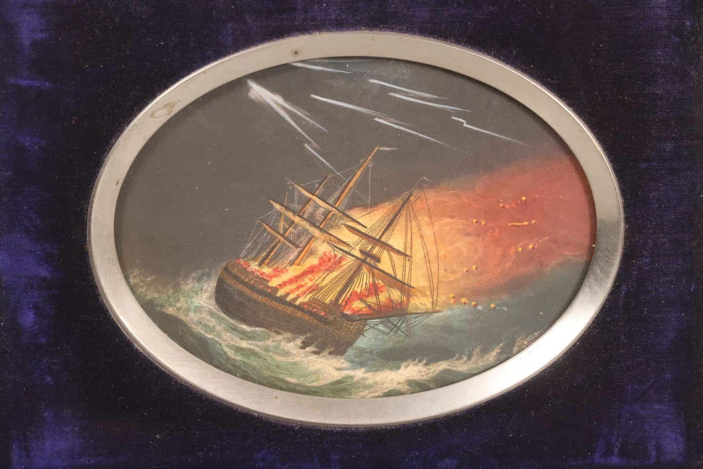 Lot 055 - Antique Hand-Colored Engraving Of Ship On Fire In Storm With Lightning, In Victorian Purple Velvet Frame With Silver Metal Surround, 8-1/2" x 6-1/2"