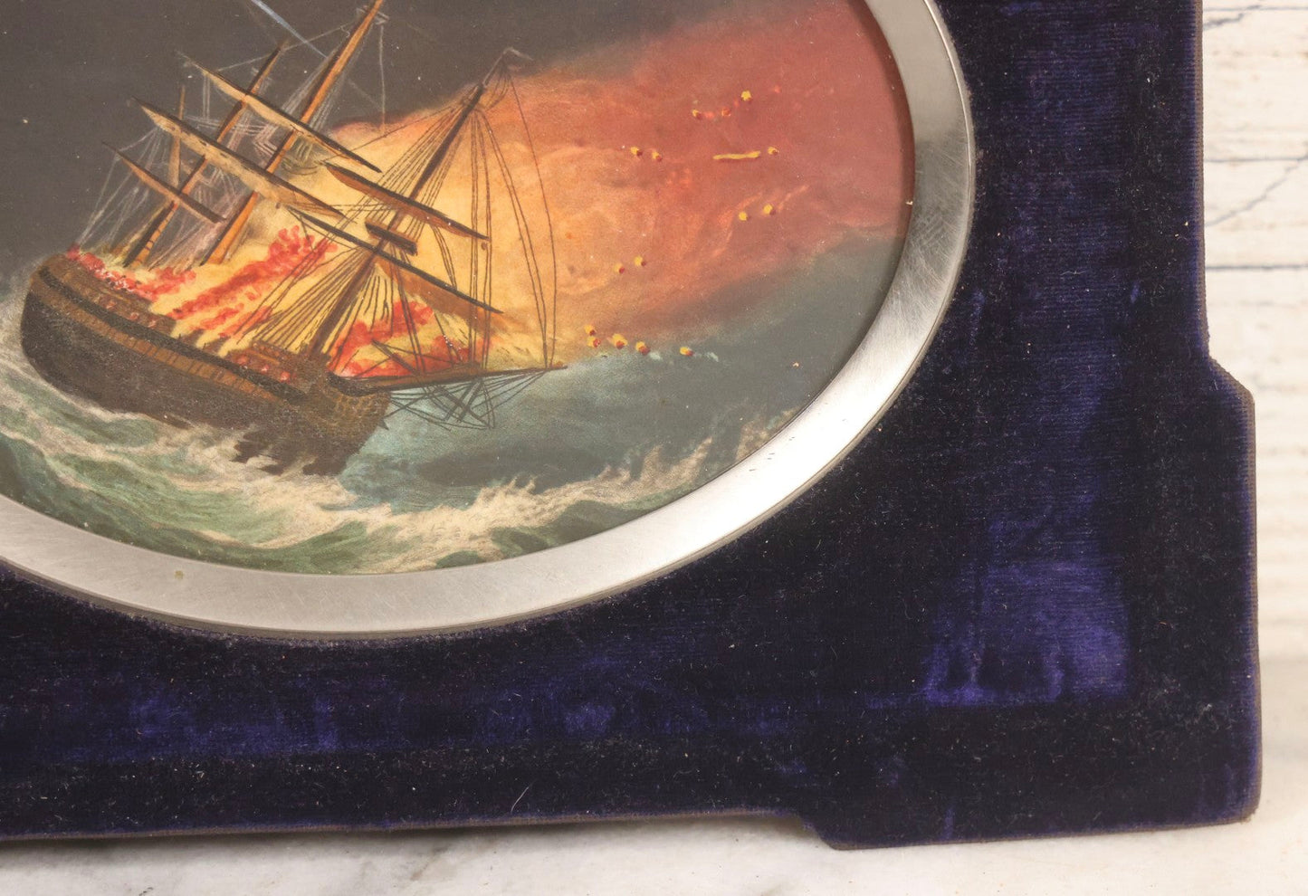 Lot 055 - Antique Hand-Colored Engraving Of Ship On Fire In Storm With Lightning, In Victorian Purple Velvet Frame With Silver Metal Surround, 8-1/2" x 6-1/2"
